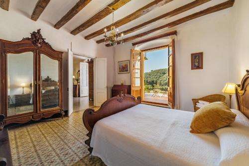 um quarto com uma cama grande e uma janela grande em Masia Can Orta em Sant Feliu de Buixalleu