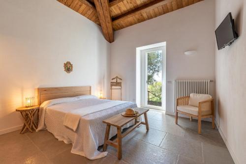 1 dormitorio con 1 cama, 1 silla y TV en Borgo Le Niche by Wonderful Italy, en Polizzi Generosa