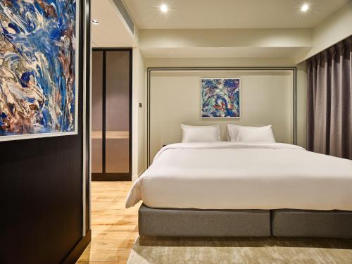 - une chambre avec un grand lit et un tableau dans l'établissement Floral Court Hotel & Residence Sukhumvit 13, à Bangkok