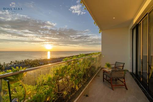 a balcony with a view of the ocean at sunset at Rosa Alba Resort & Villas Tuy Hoa in Tuy Hoa