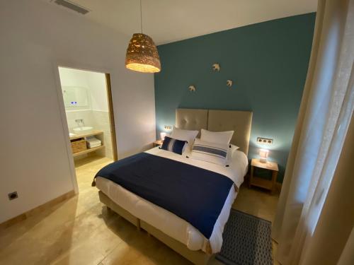 sypialnia z dużym łóżkiem i niebieską ścianą w obiekcie Les Logis de Cocagne w mieście Saint-Rémy-de-Provence