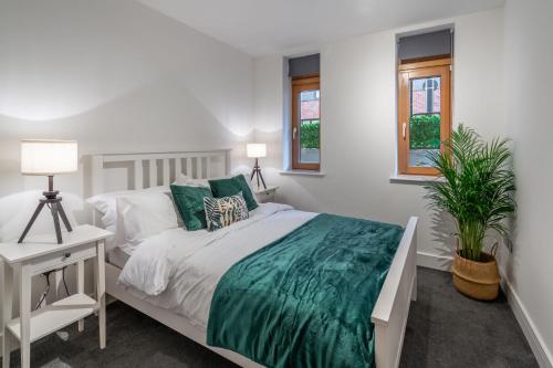 a white bedroom with a bed and a desk and windows at Mailbox 2 bed Apartment Birmingham City Centre - Free Parking in Birmingham