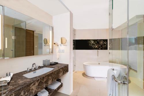 a bathroom with a tub and a large mirror at Courtyard by Marriott Agra in Agra