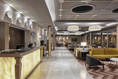 a lobby with a bar with couches and tables at TITANIC Comfort Mitte in Berlin