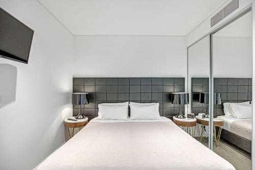 a bedroom with a large white bed and mirrors at Hidden gem studio in the heart of Chatswood in Sydney