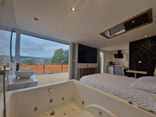 um quarto com uma grande banheira e uma grande janela em L'expérience LOVE ROOM em Saint-Jean-Bonnefonds