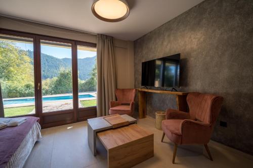 a hotel room with a bed and a tv and a table at Evritos Villas & Suites with pool in Karpenisi