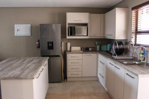 a kitchen with white cabinets and a stainless steel refrigerator at Annexure A - Lovely brand new 2 bedroom flat in Groenkloof in Pretoria