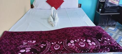 uma cama com um cobertor roxo e branco em Poddar Retreat Managed by Wheels And Wings em Dām Dim