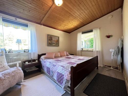 a bedroom with a bed and two windows at Cozy cottage in Kil near lake Fryken in Kil