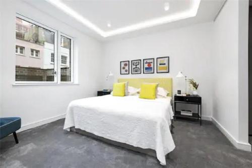 a white bedroom with a large bed with yellow pillows at Exclusive Premium St James Apartment in London