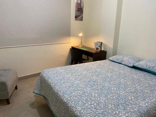 a bedroom with a bed and a desk with a lamp at GARZOTA SUITE DEL ARTE 3er Piso in Guayaquil