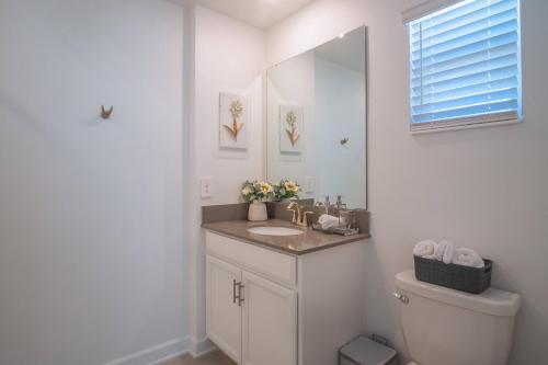 a bathroom with a sink and a toilet and a mirror at Beautiful 5bedroom Townhome w Water Park in Kissimmee