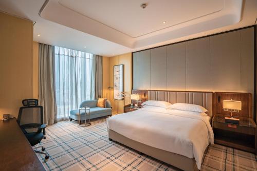 a hotel room with a large bed and a chair at Hilton Fuzhou in Fuzhou
