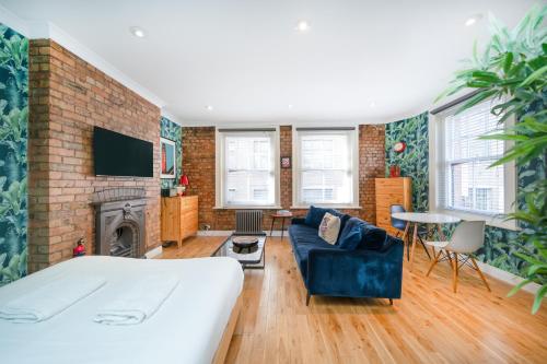 a bedroom with a bed and a couch and a fireplace at Crashpads Shoreditch Apartments - Brick Lane Mini Lofts in London