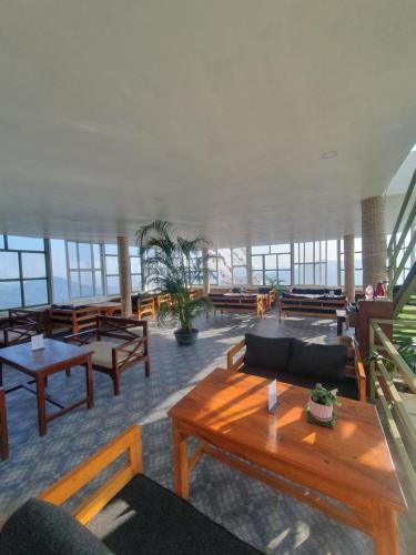 a large room with tables and benches and windows at Dhikidada Resort in Pokhara