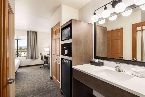 a hotel bathroom with a sink and a mirror at Days Inn & Suites by Wyndham Bozeman in Bozeman