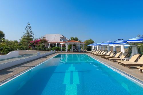a large swimming pool with lounge chairs and umbrellas at Nirvana Beach Hotel in Theologos