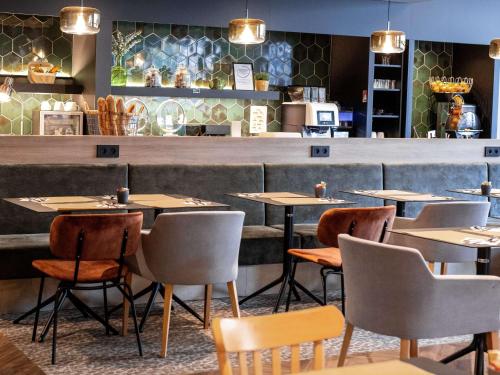 a restaurant with tables and chairs in front of a counter at Mercure Valenciennes Centre in Valenciennes