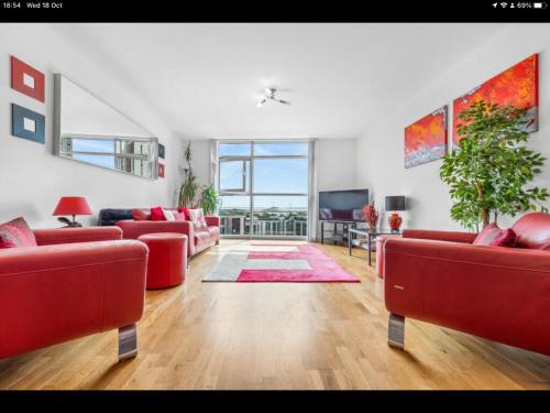 uma sala de estar com sofás vermelhos e uma televisão em Stunning Spacious City Apartment with free parking em Cardiff