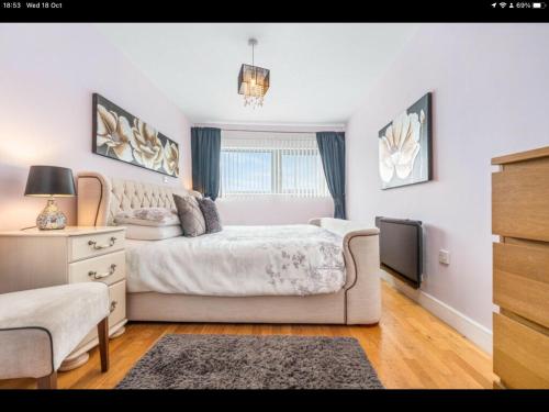 a white bedroom with a bed and a television at Stunning Spacious City Apartment with free parking in Cardiff
