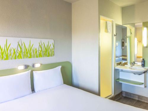1 dormitorio con 1 cama y baño con lavamanos en ibis budget Bordeaux Sud, en Villenave-dʼOrnon