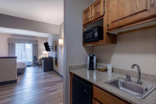 a kitchen with a sink and a living room at Baymont by Wyndham Kirksville University Area in Kirksville