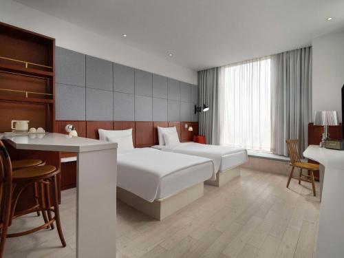 a hotel room with two beds and a desk at Novotel Shanghai Hongqiao Exhibition in Shanghai