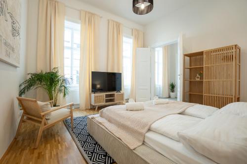 Vibrant 107 m2 flat in the city center في فيينا: غرفة نوم بيضاء بسرير كبير وتلفزيون