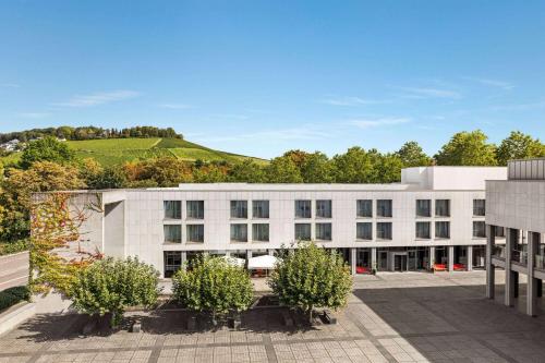 ein weißes Gebäude mit einem Hügel im Hintergrund in der Unterkunft Vienna House Easy by Wyndham Trier in Trier