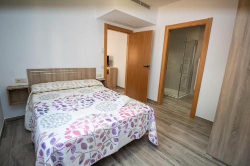 a bedroom with a bed with a purple and white comforter at Apartamentos 7 puentes sierra Cazorla Casa Tejo in Burunchel