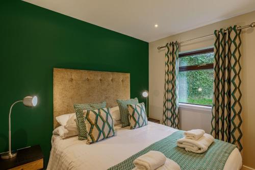 a green bedroom with a bed with towels on it at Birch Lodge 23 with Hot Tub in Newton Stewart