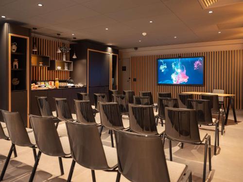 uma sala de conferências com cadeiras e uma televisão de ecrã plano em Novotel Paris Val de Fontenay em Fontenay-sous-Bois