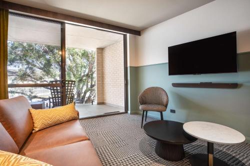 uma sala de estar com um sofá e uma televisão de ecrã plano em The Brook by Nightcap Plus em Brisbane