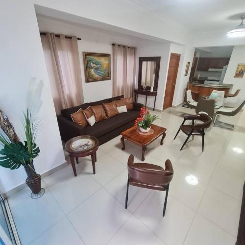 ein Wohnzimmer mit einem Sofa, Tischen und Stühlen in der Unterkunft Apartamento completo en Bella vista 1 o 2 dormitorios in Santo Domingo