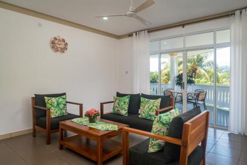 a living room with a couch and chairs and a table at 340 Degrees Mountain View Apartments in Anse a La Mouche
