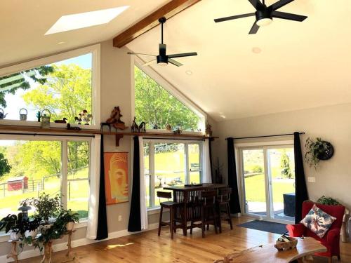 ein Wohnzimmer mit einem Tisch, Stühlen und Fenstern in der Unterkunft Zen Designed Guest Suite with PRIVATE 2-mile Trail Loop in Uxbridge
