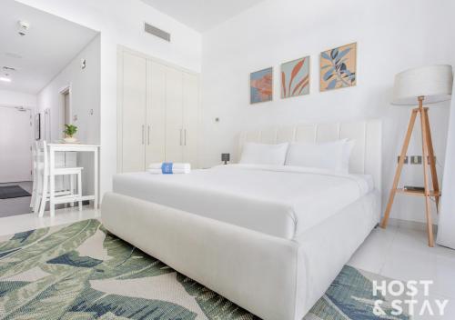 a white bedroom with a large white bed in it at Studio in Loreto 1A, DAMAC Hills - Host & Stay in Dubai