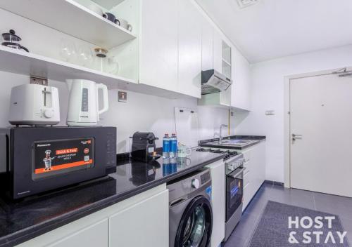 a kitchen with a washer and dryer on a counter at Studio in Loreto 1A, DAMAC Hills - Host & Stay in Dubai