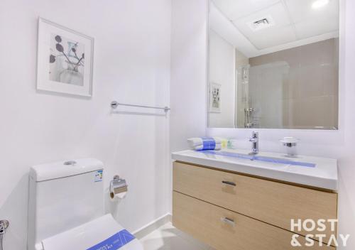 a white bathroom with a toilet and a sink at Studio in Loreto 1A, DAMAC Hills - Host & Stay in Dubai