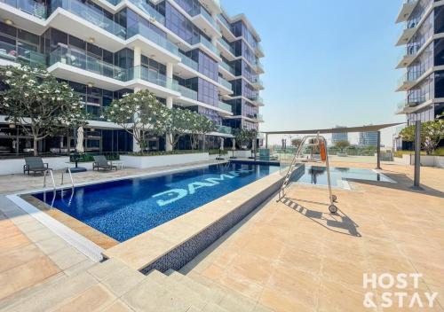a swimming pool in front of a building at Studio in Loreto 1A, DAMAC Hills - Host & Stay in Dubai