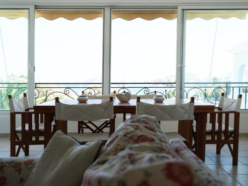 sala de estar con mesa, sillas y ventanas en Orfeas Villa Porto Rafti, en Porto Rafti