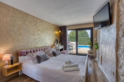 a bedroom with a large bed with a flat screen tv at Holiday house Marinela with Private Pool and Fenced Garden in Radetići