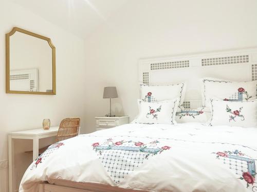 a bedroom with a white bed with pillows and a mirror at Place Sainte Marguerite in Provins