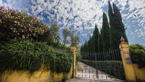 a fence with plants and trees and a cloudy sky at Tuscany Villa Gorello. Villa in Toscana. Jacuzzi con tetto in cristallo,piscina in Arezzo