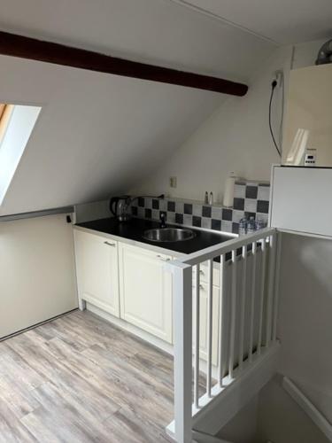 una pequeña cocina con fregadero y nevera. en Kampen NL 28-1, en Kampen