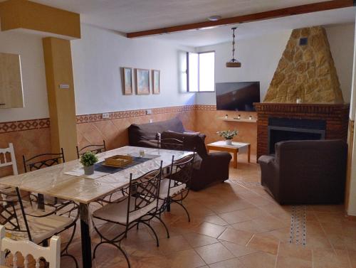 La Casa de la Buhardilla في Fondón: غرفة معيشة مع طاولة ومدفأة