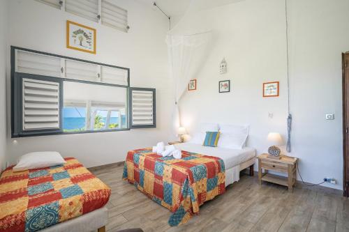 - une chambre avec 2 lits et une fenêtre dans l'établissement Villa des Raisiniers : piscine, vue et accès mer direct, spot de kitesurf, au Vauclin