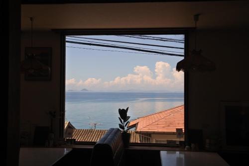 une grande fenêtre avec vue sur l'eau dans l'établissement 海に恋する泊まれる喫茶店 ポパイ, à Iyo