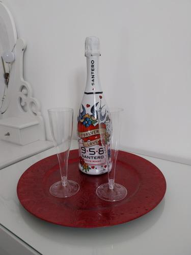 una bottiglia di birra e due bicchieri su un piatto rosso di Suite al Borgo ad Aversa